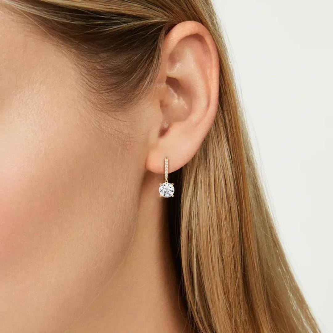 Featuring several small zircons gracefully cascading down to a stunning large zircon at the end of the drop, these earrings radiate a captivating sparkle that adds a touch of glamour to any occasion.